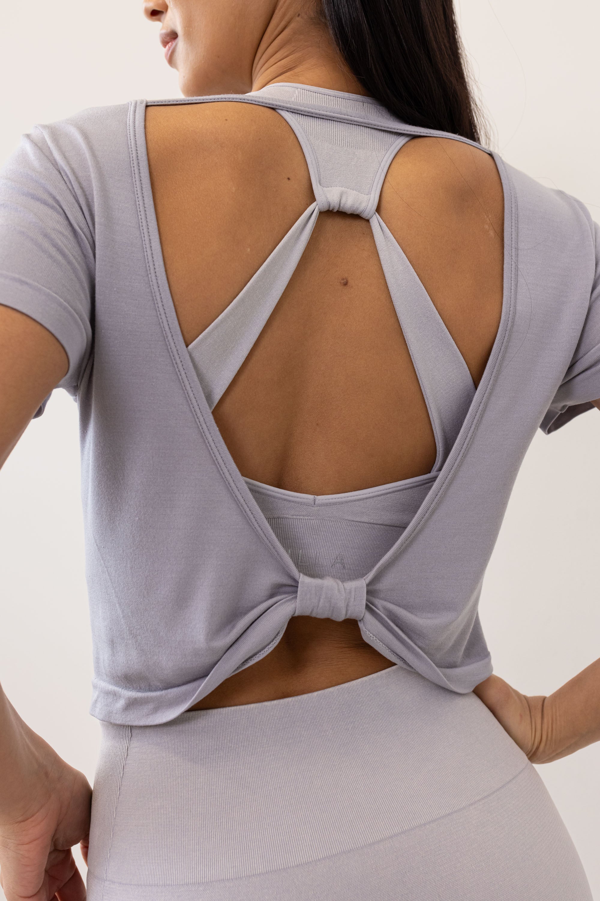 Meet our light grey Frances Modal Tee - your go-to for yoga or any workout! With a cropped length and low back, it's perfect for layering over leggings and a sports bra. Crafted from gentle Lenzing modal fabric blended with recycled polyamide, it offers unmatched softness and comfort. Cut to meet your leggings' waistband, it's a versatile must-have for your activewear collection. Experience comfort and style with Frances Modal Tee by Jilla Active